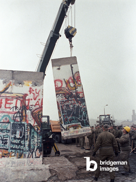 Una lastra del muro di Berlino viene sollevata da una gru della Germania dell'Est a Potsdamer Platz mentre fanno posto a un altro valico di frontiera nel 1989