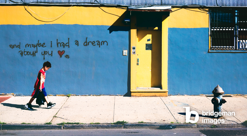 fotografia a colori di bambino di fronte a un muro con graffiti